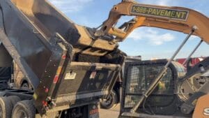 Skid steer taking asphalt from dump truck